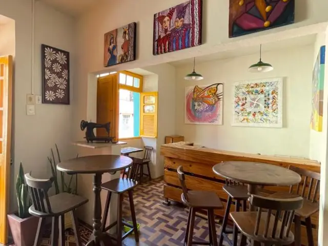 La salle du petit-déjeuner de Hostel Canto dos Artistas, avec des tables en bois et des tableaux